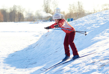 Girl enjoying cross-country skiing down in sunny day