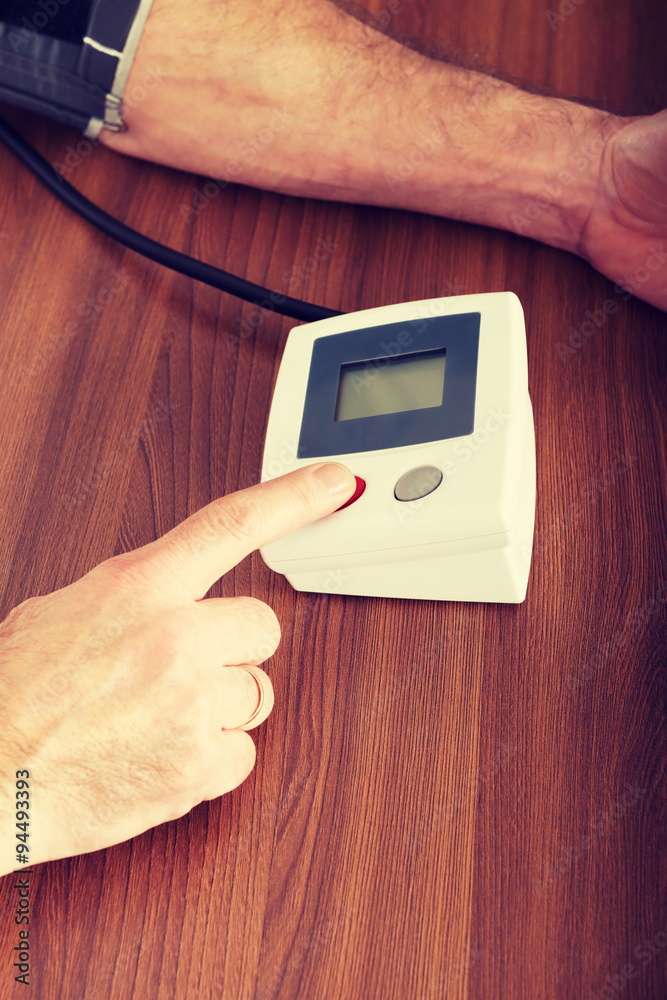 Wall mural man checking his blood pressure at home