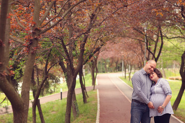 Fototapeta premium Happy and young pregnant couple embracing in nature