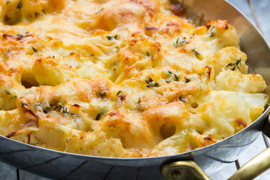 Vegetarisches Blumenkohlgratin mit Käse überbacken, in Edelstahlpfanne angeschnitten