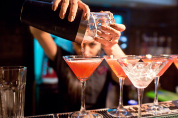 Le barman de fille prépare un cocktail dans la boîte de nuit