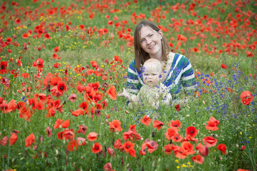 Woman with baby in a field of red poppies