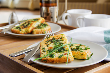 Breakfast for two: French toast with fresh herbs and tea on a wooden table