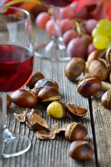 Geröstete Maroni mit neuem Rotwein, weiße und rote Weintrauben im Hintergrund