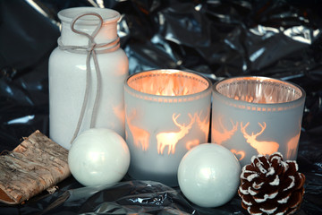 red Christmas background with three tea candle holders decorated with a wooden reindeer , pine apple and christmas ball