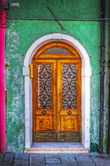 Fototapeta na wymiar wooden door in a green rustic wall in Burano