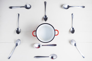 Top view of empty pot with spoons on symmetry. Concept of hunger and food time.