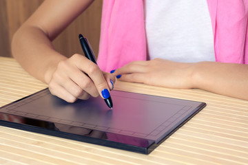 Woman in pink scarf and blue manicure draws on the tablet at a w