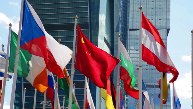 Many bright flags waving near modern office building 