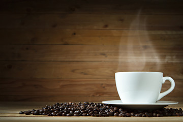 Coffee cup and coffee beans on wooden background.