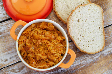 Traditional Polish bigos in saucepen and slices of freshly baked rustic bread
