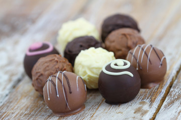 Selection of white, milk and dark chocolates and pralines on rustic wooden surface
