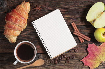 Croissant with coffee and opened notepad