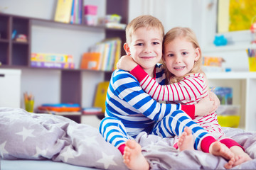 Obraz premium Two happy siblings in sleepwears in bed