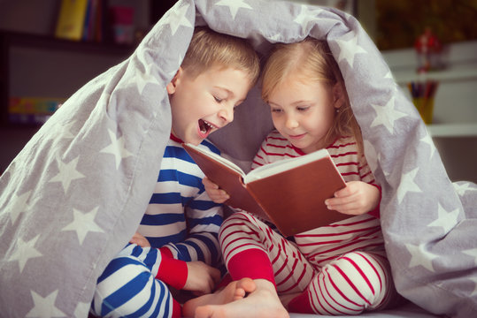 Happy Siblings Reading Book Under Cover