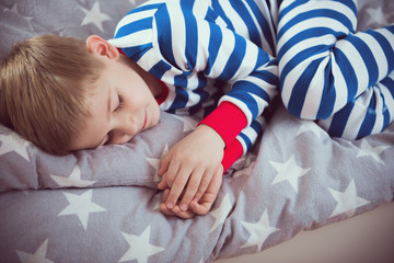 Cute little boy sleeps in pajames on bed. Fokus above © spass