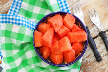 Bowl of fresh watermelon cubes on green and white checkered cloth

