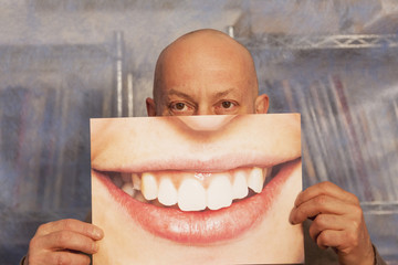 bald man holding a card with a big smile on it