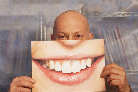 bald man holding a card with a big smile on it