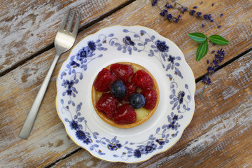Crunchy tartelette with fresh fruit on vintage plate on rustic wood
