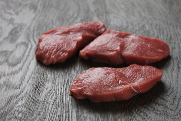 Raw beef steaks on a dark wooden board