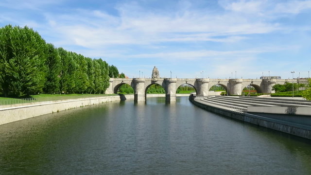 landmark of green water river Manzanares at garden park forest and ancient stone Toledo Bridge made in year 1718 in Madrid city Spain Europe
