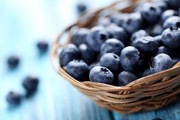 Tasty blueberries in basket on a blue wooden table