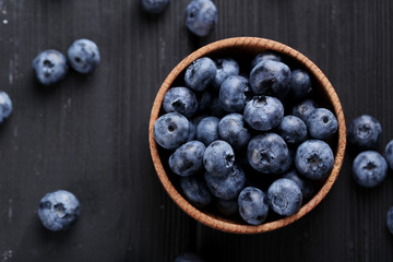 Tasty blueberries in bowl on a black wooden table