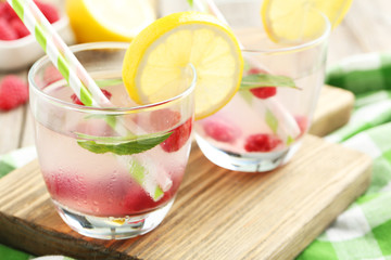 Raspberries and juice in glass on cutting board on grey wooden b