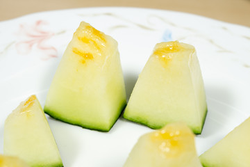 Chunk of Santa Claus melon on a white dish