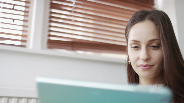 4K Young pretty woman using a digital tablet whilst relaxing at home