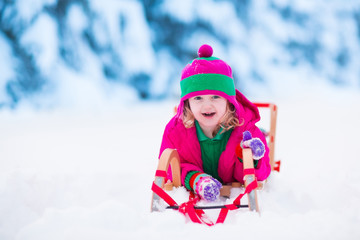 Fototapeta na wymiar Little girl playing in snowy winter forest