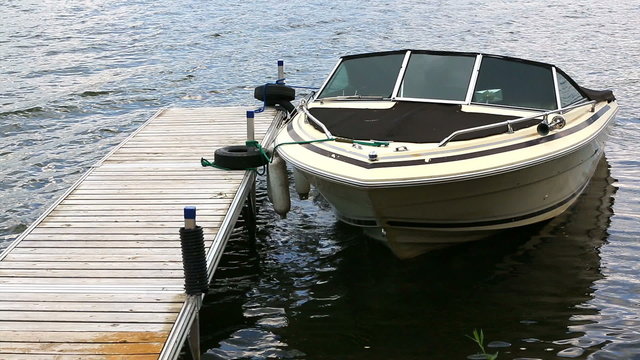 Boat and Dock. an older motor boat floats in the water. tethered to the dock.

