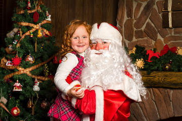 Santa Claus holds on hands happy little girl.