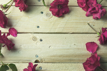 Frame of red roses on wooden background