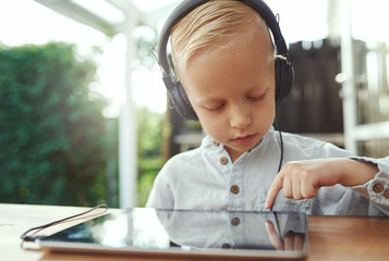 Pensive little boy selecting a new soundtrack