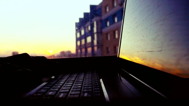 Women hands prints with laptop in the office at beautiful sunset on blurred architectural background