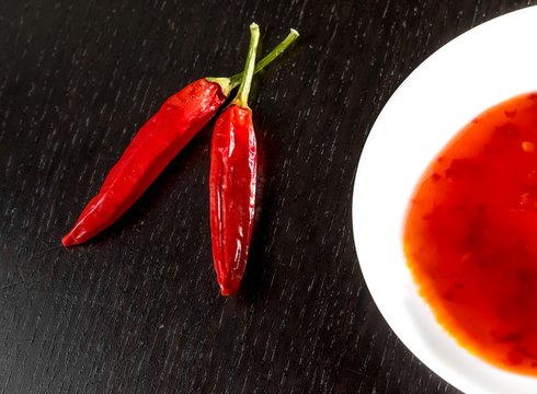 spicy hot tomato sauce as a snack or appetizer in a white disc near spicy peppers