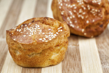 Two cornbread muffins with sesame photographed on wooden table. Studio shot.