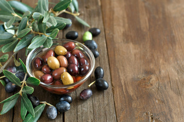 Fresh olives and olive branch on wood background