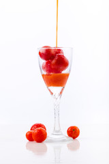 tomato juice being poured into a glass with cherry tomatoes on a white background with reflection, healthy drink for gourmet