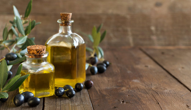 Olive oil and fresh olives on wood background