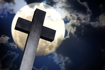 stone cross against the moon, dramatic clouds in the night sky