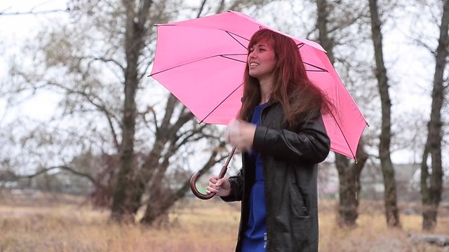 The frozen woman with an umbrella costs in the rain and speaks by phone