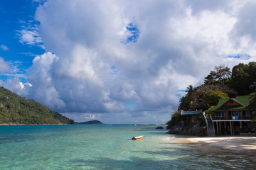 Obraz premium green tropical island, cloudy sky and small resort.