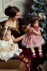 Young mother and her two little daughters near Christmas tree 