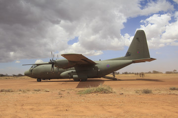 Fototapeta na wymiar Military aircraft lands on field airstrip to deploy troops