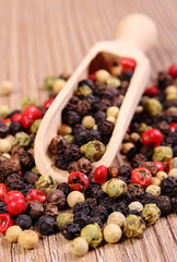 Fresh colored pepper with spoon on wooden background