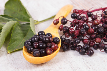 Heap of elderberry with wooden spoon on old wooden background, healthy food