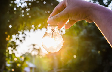 and holding a light bulb with sunset power concept